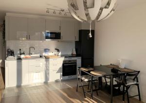 a kitchen with white cabinets and a black table and chairs at Tu casa a 10 minutos de París! in Bagneux