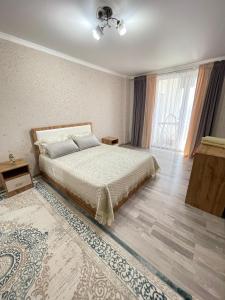 a bedroom with a bed and a large window at Просторная квартира 3 х ком в Новом районе in Shymkent