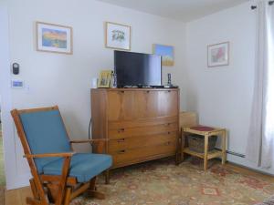a living room with a tv and a chair and a dresser at Discover Downeast Maine - Comfortable Home Base 37 in Ellsworth