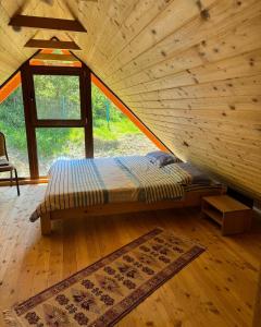 a bed in a wooden room with a window at Cabana Izvorul Rece Maramureş in Baia-Sprie
