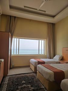 a hotel room with two beds and a large window at Leading Wings Beach Apartments in Sur