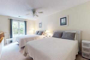 two beds in a white room with a ceiling fan at Club Villas 1A in Sunset Beach