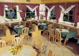 a restaurant with green tables and chairs and windows at Landhotel Goldener Stern in Trautskirchen