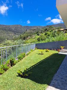 a backyard with a fence and grass and mountains at Hills and Atlantic Ocean retreat - Conceição House in Calheta
