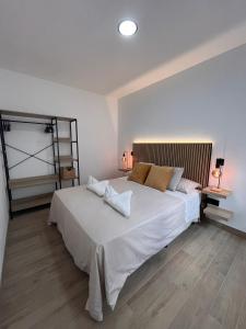 a bedroom with a large white bed and two lamps at Apartamento Peña in Sardina