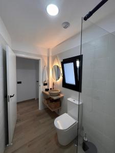 a white bathroom with a toilet and a sink at Apartamento Peña in Sardina