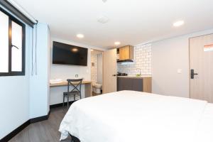 a bedroom with a white bed and a desk at Terrazas in Bogotá