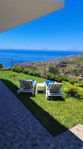 two chairs and a table on the grass near the ocean at Hills and Atlantic Ocean retreat - Conceição House in Calheta +11 photos