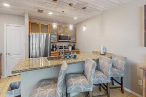 a kitchen with a counter with bar stools and a sink at Star Beachside Condominiums 106 in South Padre Island