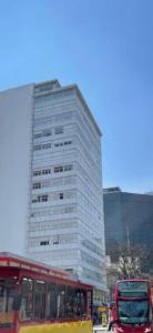 Un palazzo alto con un autobus rosso davanti di carso alameda a Città del Messico