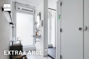 a bathroom with a shower door and a mirror at NunoHotel in Cologne