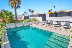 - une piscine avec des chaises longues à côté d'une maison dans l'établissement Villa Kalma - Torreguadiaro - Sotogrande, à Sotogrande