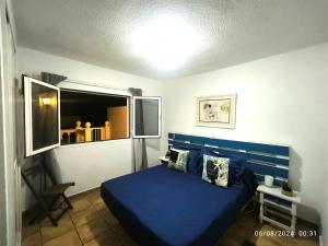a bedroom with a blue bed and a window at Casa Frasca in Teguise