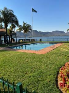 una piscina en un parque junto a un cuerpo de agua en 124 Key West, en Hartbeespoort