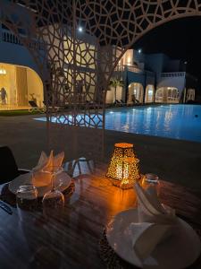 a table with plates and a lamp next to a pool at Villa La Falaise in Oualidia