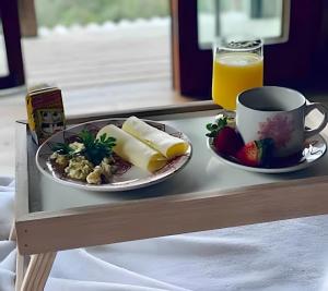 a tray with a plate of food and a cup of orange juice at Casa dos Alpes com Jacuzzi hidro e Lareira in Santo Amaro da Imperatriz