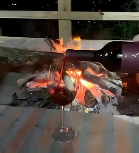a glass of wine is being poured over a fire at Casa dos Alpes com Jacuzzi hidro e Lareira in Santo Amaro da Imperatriz