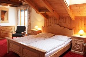 een slaapkamer met een groot bed en een stoel bij Himmelbauer Apartments in Söbriach