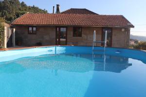 a large blue swimming pool in front of a house at Cantinho de Paços in Souzelo