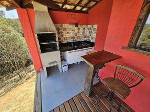 a kitchen with a stove and a table on a deck at Chalés Vila Real - Tranquilidade na Serra de Carrancas - Piscina com uma vista espetacular do Pôr do Sol in Carrancas