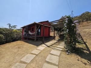 a small red house with flowers growing around it at Chalés Vila Real - Tranquilidade na Serra de Carrancas - Piscina com uma vista espetacular do Pôr do Sol in Carrancas