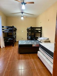 a room with two beds and a ceiling fan at Casa com Piscina Aquecida Mongaguá in Mongaguá