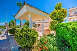a large building with trees and bushes in front of it at Bungalow Carabassi Mediterraneo 3 Pool and roof terrace in Puerto Marino