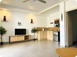 a living room with a flat screen tv and a kitchen at Serenity Lodge Tahiti Fare Haumana in Outu Maoro