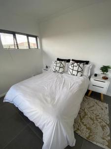 ein weißes Bett in einem Schlafzimmer mit einem Fenster in der Unterkunft Cottage on 36 Neethlingshof in Kapstadt