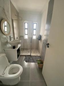 ein weißes Badezimmer mit Toilette und Waschbecken in der Unterkunft Cottage on 36 Neethlingshof in Kapstadt