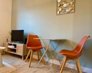 2 orangefarbene Stühle und ein Tisch in einem Zimmer in der Unterkunft Appartement proche Centre-ville- Fibre in Saint Lo