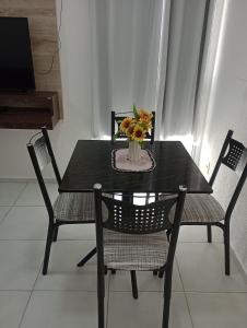 a black table with two chairs and a vase with flowers at Plaza Fraga Maia in Feira de Santana