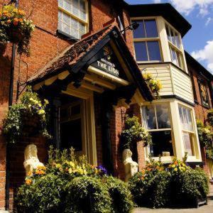 un edificio de ladrillo con flores delante en The Lion Waddesdon, en Waddesdon