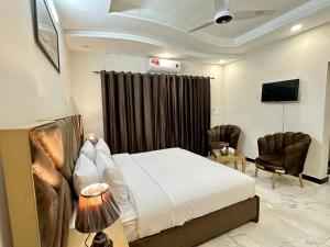 a hotel room with a bed and two chairs at Western Lodge Guest House Islamabad in Islamabad