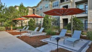 a patio with chairs and umbrellas in front of a building at Landing at The Grayson - 1 Bedroom in Cypressdale in Spring