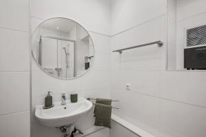 a white bathroom with a sink and a mirror at Ferienwohnung Blaßdörfer - Traumhafte Altbauwohnung mit Self-Checkin und 93 qm2 in Bad Kissingen +18 photos