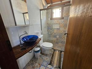 a bathroom with a toilet and a blue sink at Chalés Vila Real - Tranquilidade na Serra de Carrancas - Piscina com uma vista espetacular do Pôr do Sol in Carrancas