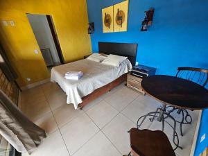 a small bedroom with a bed and a table at Chalés Vila Real - Tranquilidade na Serra de Carrancas - Piscina com uma vista espetacular do Pôr do Sol in Carrancas
