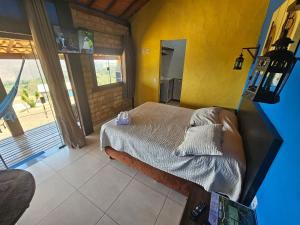 a bedroom with a bed and a yellow wall at Chalés Vila Real - Tranquilidade na Serra de Carrancas - Piscina com uma vista espetacular do Pôr do Sol in Carrancas