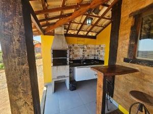 a kitchen with a stove top oven in a room at Chalés Vila Real - Tranquilidade na Serra de Carrancas - Piscina com uma vista espetacular do Pôr do Sol in Carrancas