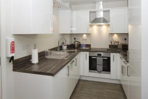 a kitchen with white cabinets and a sink and a stove at House of Fisher - Beneficial House in Bracknell