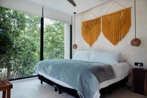 a bedroom with a bed and a large window at The Village K´AAX in Tulum