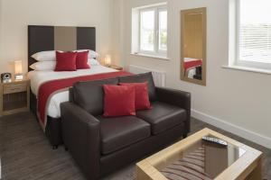 a bedroom with a bed and a couch and a chair at House of Fisher - Beneficial House in Bracknell