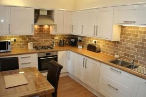 Una cocina con gabinetes blancos y una mesa de madera. en The Imperial Apartment, en North Berwick