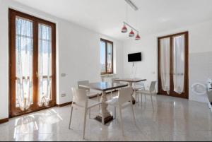 una sala da pranzo con tavolo, sedie e finestre di La Terrazza Guest House a San Zeno