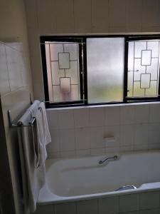 a bathroom with a bath tub and two windows at Bed on 22 in Ballito +15 photos