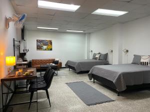 a room with two beds and a desk and a couch at San Jose Downtown Suites in San José