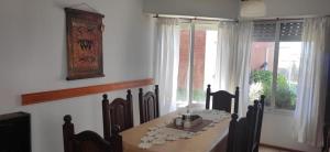 ein Esszimmer mit Tisch und Stühlen und Fenstern in der Unterkunft Duplex frente al Mar en Villa Gesell in Villa Gesell