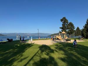 eine Gruppe von Menschen in einem Park mit einem Spielplatz in der Unterkunft Mayor's Lake and Ski Suite in Sandpoint