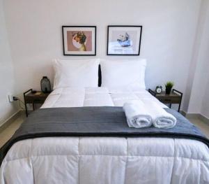 a large white bed with two folded towels on it at Modern City Condo El Millon in El Jobo de Mendoza